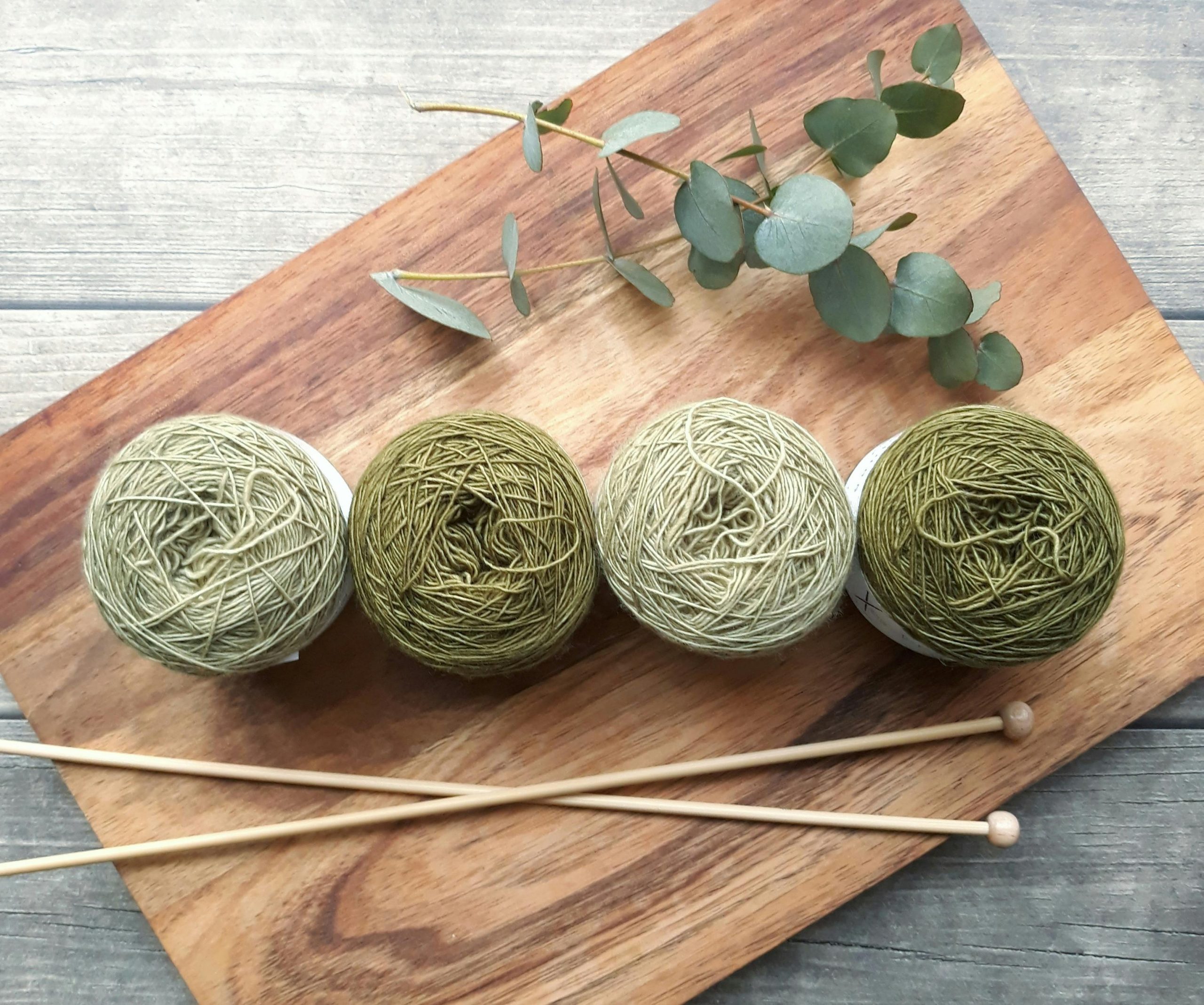 green yarn in various shades arranged on a wooden surface